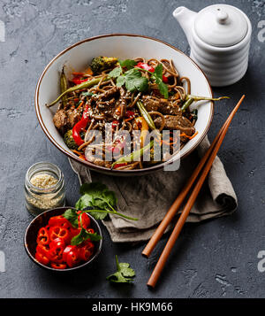 Faire sauter les nouilles soba au boeuf et légumes dans un bol de pierre sombre contexte Banque D'Images