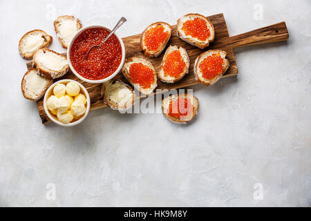 Salmon caviar rouge dans un bol et sandwichs sur planche à découper en bois sur fond blanc copy space Banque D'Images