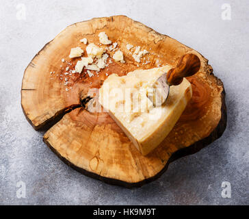 Fromage Parmesan sur planche de bois avec un couteau à fromage sur fond de béton gris Banque D'Images