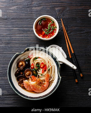 Nouilles ramen aux crevettes et champignons shiitake au bouillon sur fond de bois foncé Banque D'Images