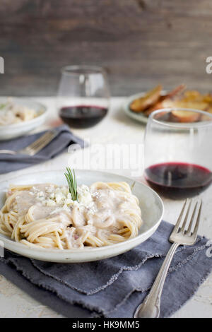 Sauce à la crème de Gorgonzola romarin spaghetti au pesto sur servi avec du vin rouge et crostini. Photographié à partir de la vue de face, sur fond blanc/jaune de couleur pêche/ Banque D'Images