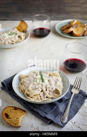 Sauce à la crème de Gorgonzola romarin spaghetti au pesto sur servi avec du vin rouge et crostini. Photographié à partir de la vue de face, sur fond blanc/jaune de couleur pêche/ Banque D'Images