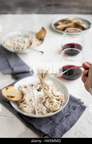 Sauce à la crème de Gorgonzola romarin spaghetti au pesto sur servi avec du vin rouge et crostini. Photographié à partir de la vue de face, sur fond blanc/jaune de couleur pêche/ Banque D'Images