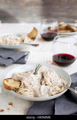 Sauce à la crème de Gorgonzola romarin spaghetti au pesto sur servi avec du vin rouge et crostini. Photographié en vue de dessus sur un blanc/jaune de couleur pêche/pl Banque D'Images