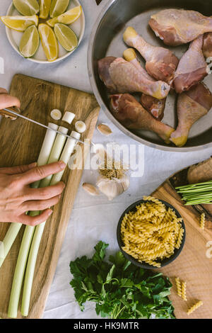 Les poireaux, couper les mains les pilons de poulet dans une casserole et un bol de pâtes sont sur le côté. Banque D'Images