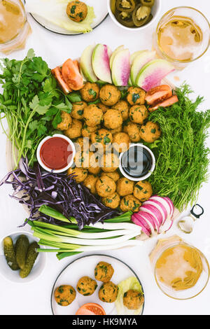 Boulghour turc et boules de lentilles servi avec des herbes, des radis, du chou rouge et accompagné de sauces à la bière. Banque D'Images