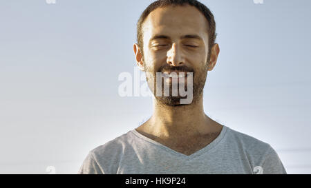 Cheerful homme sourit avec les yeux fermé Banque D'Images