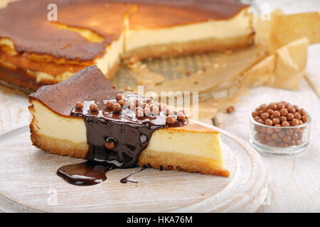 Tranche de gâteau au fromage avec du chocolat fondu et des boules de chocolat Banque D'Images