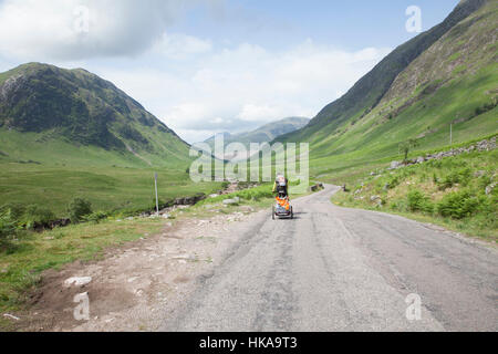 Homme randonnée à vélo sur la route à côté de la rivière Etive dans Glen Etive dans les Highlands, en Écosse. Banque D'Images