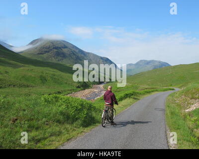 Un cycliste à vélo sur une route de campagne tranquille vers Glen Etive dans le nord-ouest de l'Ecosse highlands UK Banque D'Images