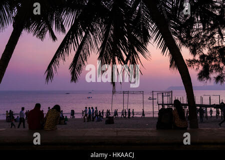Des couples et beachwalkers silhouetté au coucher du soleil sur la plage de Chowpatty, Mumbai (Bombay), Inde. Banque D'Images