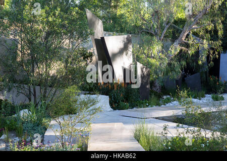 Un chemin de jardin moderne contemporain avec des écrans en métal menant à un coin salon mixte plantation herbacée et parterres de fleurs jardin de gravier Royaume-Uni Banque D'Images