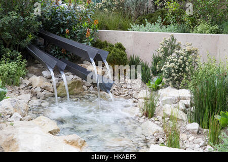 Jardin moderne et contemporain avec un petit étang et de l'eau de rill, cascade de chute d'eau au-dessus de pierres et de rochers au Royaume-Uni Banque D'Images