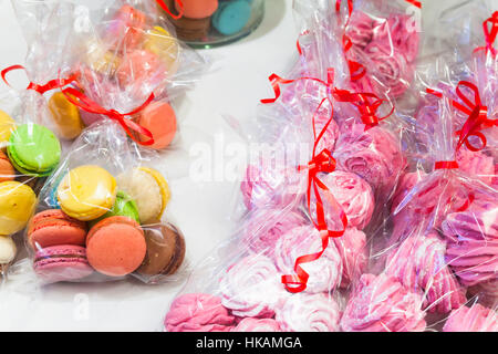 Boîtes de macarons français traditionnels colorés et meringues rose blanc sur la lutte contre le marché Banque D'Images