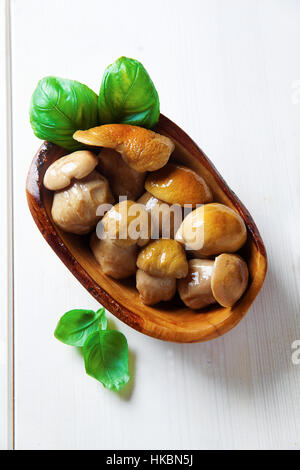 Champignons blancs marinés dans bol en bois sur blanc au basilic Banque D'Images