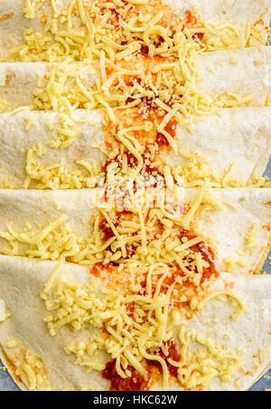 Cuisine mexicaine traditionnelle faite maison burrito, fajitas, enchiladas, quesadillas ou les tacos avec le fromage cheddar sur un support papier, prêt pour la cuisson dans l'o Banque D'Images