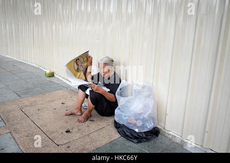 Une femme thaïlandaise qui recueille des roseaux bidons sur le roi Bhumibol Adulyadej devant le Palais Royal Banque D'Images