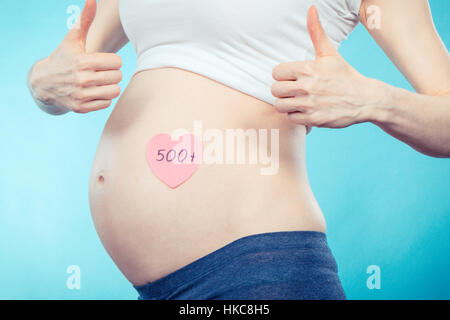 Pregnant woman holding feuille de papier avec l'inscription 500 + et holding Thumbs up, programme social et politique en Pologne Banque D'Images