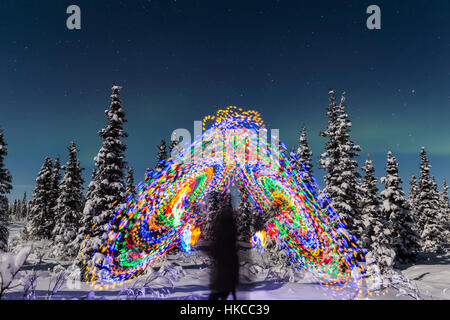 L'Aurora Borealis danse sur le dessus d'Un vibrant Spiral Light Painting, la figure floue d'Un homme au milieu de la lumière Painting, Moonlig... Banque D'Images