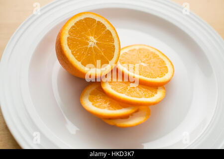 Une orange en tranches sur une assiette blanche Banque D'Images