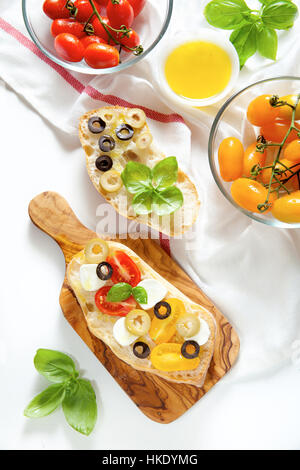 Bruschetta à la tomate cerise rouge et jaune, basilic frais, olives vertes et noires et de mozzarella Banque D'Images