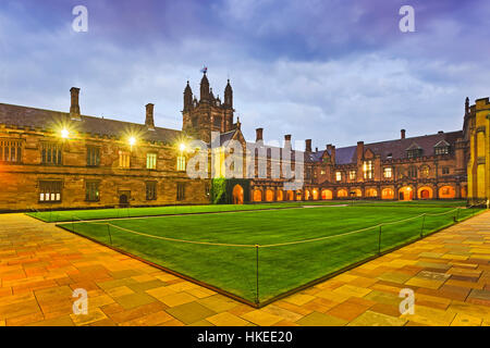 Cour intérieure autour de pelouse verte d'édifices historiques nommé 'carré' dans l'Université de Sydney au coucher du soleil avec un éclairage lumineux. Banque D'Images