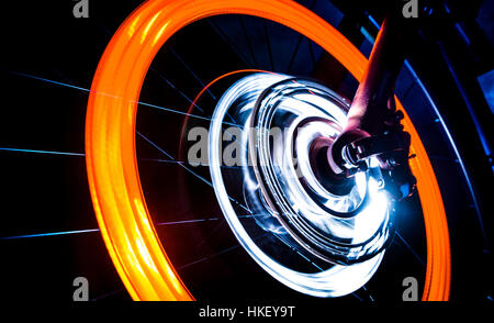 Spinning Bike roue avec feux orange et blanc sur fond sombre Banque D'Images