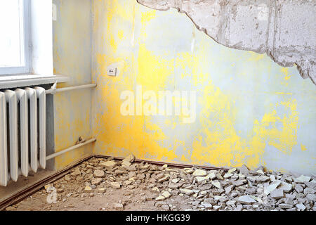 Vide intérieur jaune sale détruit avec vintage radiateur. La réparation des appartements avec old rusty radiateur de chauffage central en fonte ou de la batterie Banque D'Images