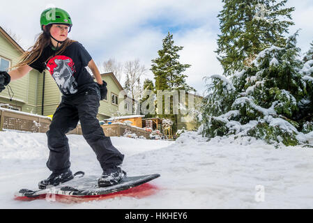 Le jeune garçon pratique le snowboard dans la neige de l'arrière-cour, Banque D'Images