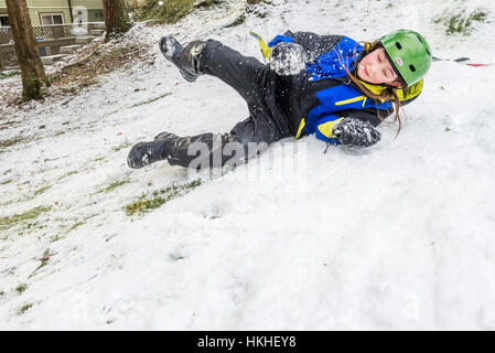 Le jeune garçon pratique le snowboard dans la neige de l'arrière-cour, Banque D'Images