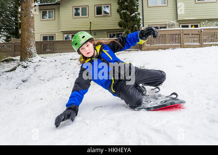 Le jeune garçon pratique le snowboard dans la neige de l'arrière-cour, Banque D'Images