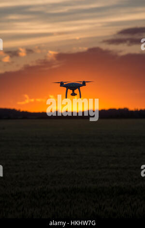 Drone silhouetté contre coucher du soleil orange Banque D'Images