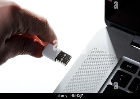Insérez une clé USB dans l'ordinateur isolé sur fond blanc Banque D'Images