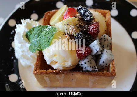 Miel pain perdu aux fruits tropicaux exotiques tels que le fruit du dragon et la banane avec de la crème glacée et une feuille de menthe Banque D'Images