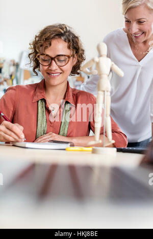 Les professionnels de la conception des femmes avec l'artiste en train de dessiner la figure de l'office de tourisme Banque D'Images