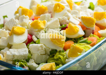 Salade avec des œufs, fromage feta et les carottes dans un bol en verre transparent Banque D'Images