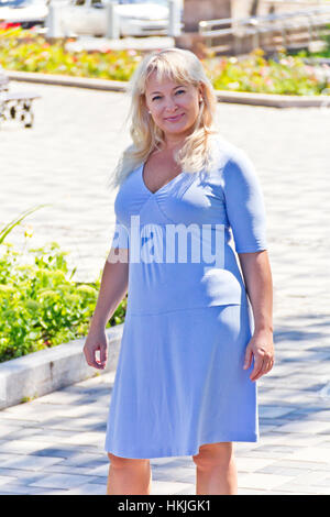 Femme blonde en bleu sur le trottoir Banque D'Images