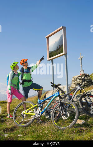 Jeune couple de vététistes regardant information board sur la pente, Zillertal, Tyrol, Autriche Banque D'Images