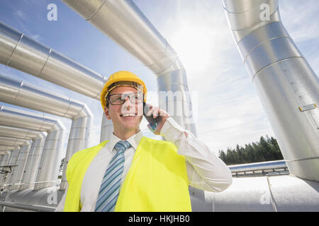 Jeune ingénieur en conversation sur téléphone mobile à l'énergie géothermique, Bavière, Allemagne Banque D'Images