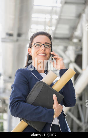 Ingénieur femelle talking on mobile phone at geothermal power station, Bavière, Allemagne Banque D'Images