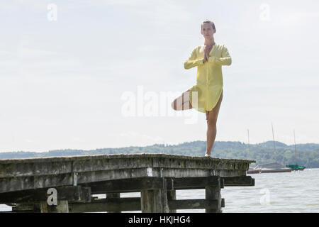 Woman doing yoga posture de l'arbre sur la jetée à l'Ammersee, lac, Haute-Bavière, Allemagne Banque D'Images