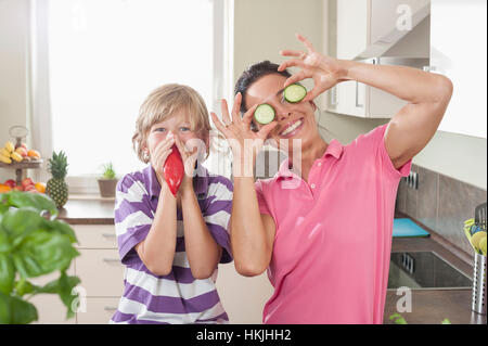 Femme avec son fils jouer avec des légumes en cuisine, Bavière, Allemagne Banque D'Images