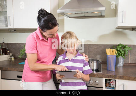 Femme avec son fils using digital tablet in kitchen,Bavière, Allemagne Banque D'Images