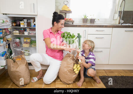 Femme avec son fils mettait des épiceries réfrigérateur,Bavière, Allemagne Banque D'Images