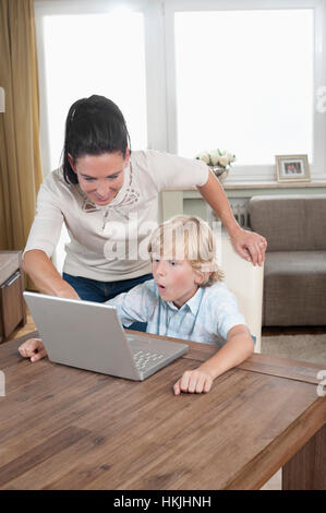 Femme avec son fils à l'aide d'ordinateur portable dans la salle de séjour,Bavière, Allemagne Banque D'Images