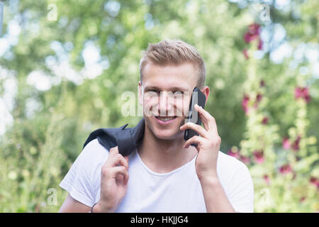 Portrait of a young man talking on mobile phone in urban garden, Freiburg im Breisgau, Bade-Wurtemberg, Allemagne Banque D'Images