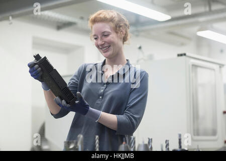 Jeune femme à la recherche d'ingénieur à l'élément de la machine dans une usine industrielle, Freiburg im Breisgau, Bade-Wurtemberg, Allemagne Banque D'Images