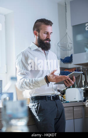 Young man using digital tablet in La cuisine, Bavière, Allemagne Banque D'Images