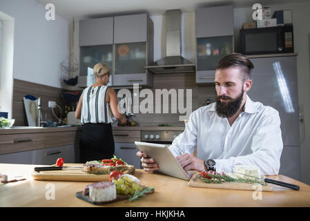 Jeune homme à la recette sur tablette numérique pour les repas dans la cuisine, Bavière, Allemagne Banque D'Images