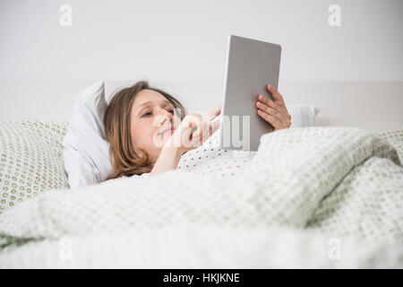 Pregnant woman Lying in Bed and using digital tablet, Munich, Bavière, Allemagne Banque D'Images